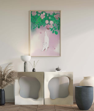 White cat stretching beneath blooming flowers in a pastel garden setting