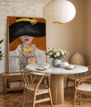Femme avec un chapeau noir orné d’une touche dorée tenant un verre à cocktail