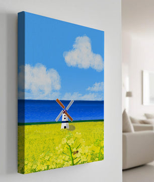 Paisaje pintoresco con molino de viento en un campo floreciente junto al mar