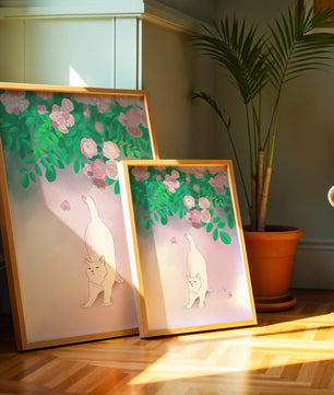 White cat stretching beneath blooming flowers in a pastel garden setting