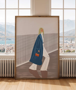 Fashionable Woman in Long Blue Coat Walking Along Corridor with Orange Handbag