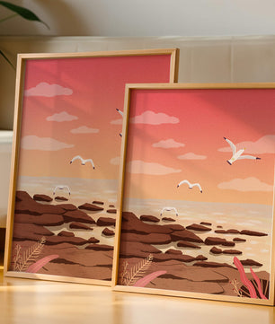 Seagulls flying over rocky coastline at sunset