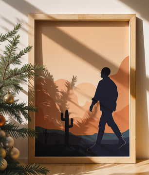 Silhouetted figure walking in desert landscape at sunset