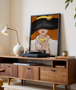 Femme avec un chapeau noir orné d’une touche dorée tenant un verre à cocktail