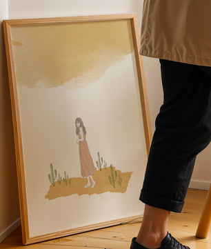 Fille en robe rose debout parmi des cactus sous un ciel aquarelle