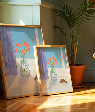 Jarrón con flores naranjas junto a una ventana con cortinas moradas