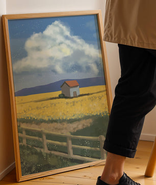Idyllic rural scene with house and yellow field under blue sky