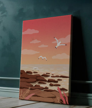 Seagulls flying over rocky coastline at sunset