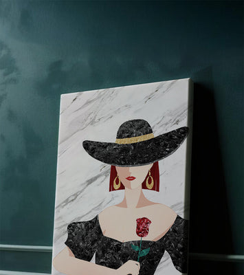 Elegant woman in wide-brimmed hat holding a rose on marble background