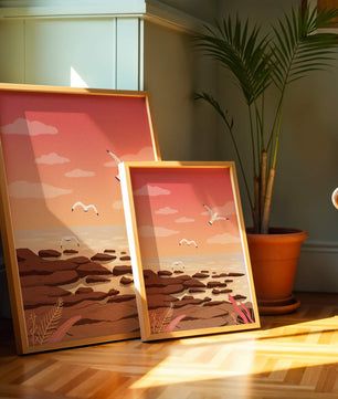 Seagulls flying over rocky coastline at sunset
