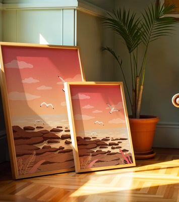 Seagulls flying over rocky coastline at sunset